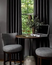 Moody, mid-century modern seating area design with two chairs and a metal base table in front of velvet curtains.