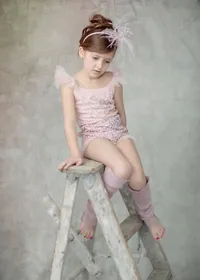 Girl in a pink sequined outfit posed on a ladder during her studio portrait session
