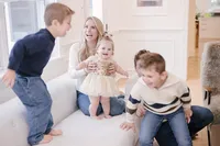 Family laughing together on a couch during their indoor portrait session