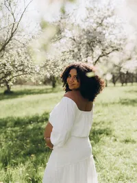 A pregnant woman smiles over her shoulder while holding her belly, by Grand Rapids maternity photography Grace Wan.