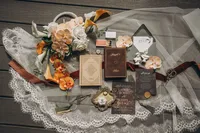 Flat lay of the bride and groom's vow books, rings, wedding stationary, florals, and a few other small things lying on the bride's veil.