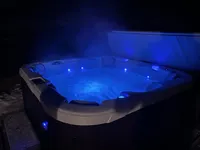 Private hot tub glowing blue at night at Brookside Retreat