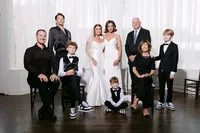 Chyan and Allison posing with their family in black formalwear for a group portrait at their wedding, by Dove and Fox