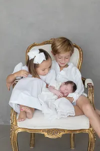 Siblings holding their newborn baby together during a studio portrait session