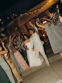 A bride and groom exit their reception as the guests form a tunnel for them with sparklers.