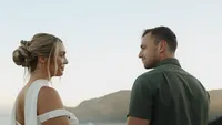bride and groom on hillside facing each other - Wedding videography still of couple standing close together on grassy hillside with mountain backdrop