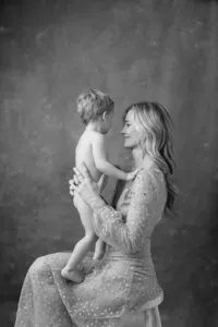 Mother holding her toddler during a studio portrait session, photographed in black and white