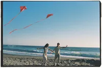 Grand Rapids couples photographer Grace Wan captures a couple running down the beach flying kits together.