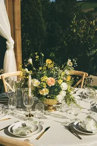 yellow and white table setting - Photograph of elegant reception table with yellow and white floral centerpiece, place settings, and glassware with ivy backdrop