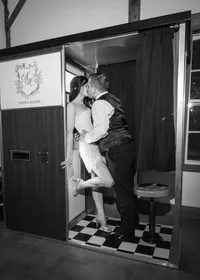 Black and white photo of Amanda and Michael kissing inside a photo booth at their wedding reception, by Dove and Fox