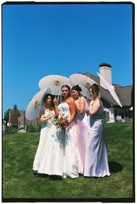 35mm film wedding photography in Grand Rapids Michigan of a bride standing with her 3 bridesmaids as they all hold white parasols.