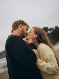 A couple is about to kiss on the beach during their engagement photoshoot with The Garden Photo + Film.