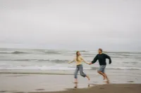 Oregon coast couples photographer Grace Wan captures a blurry photo of a couple holding hands as they run down Cannon Beach together.