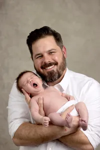 Father holding his yawning newborn during a studio portrait session
