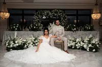 bride and groom in front of white wedding styling and heart-shaped floral arch