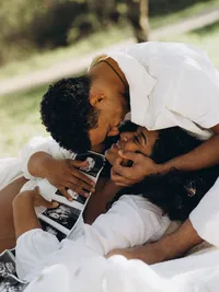 Grand Rapids maternity photos of a husband about to kiss his wife as she holds their sonograms.