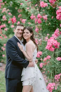 Couple embracing in a garden of pink roses during their engagement session
