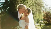 Wedding videography still of couple kissing in outdoor garden setting with trees and natural lighting
