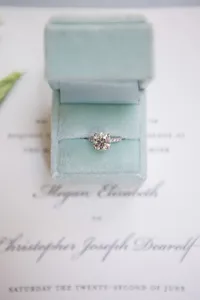 Diamond engagement ring displayed in a velvet box resting on a calligraphy wedding invitation