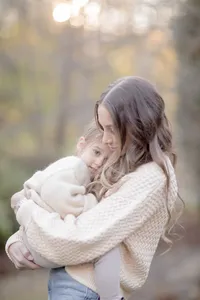 Mother embracing her child cheek to cheek in autumn light