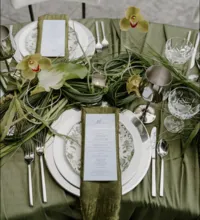 a green tablescape with green goddess calla lilies, bear grass, garlicscapes, and wired cymbidium orchid blooms. made by a seattle wedding florist who services tacoma, seattle, puyallup and the greater pnw