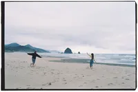 Couples photography of a man and woman running down the beach in Michigan, their arms in the air.