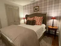 Basement bedroom with plaid accent wall and bedside lamps at Brookside Retreat