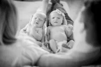 Newborn twins held together, photographed in black and white