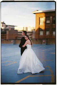 35mm film wedding photography of a bride holding her groom from behind as he looks off into the distance.