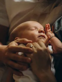 Close up portrait of a newborn baby as he's held by his parents, by Grand Rapids family photographer Grace Wan.