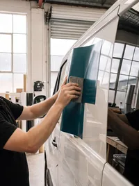 Fitter smoothing teal vinyl onto a glass panel
