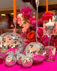 close up of Deighton Lodge wedding table styling, bright pink table decor and colourful table centrepiece with candles and disco balls
