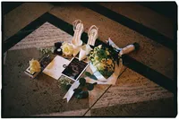Flat lay of the bride's shoes, rings, wedding bouquet, and wedding stationary.