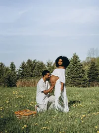 A man kisses his pregnant wife's belly as she smiles at the camera during their maternity photoshoot in Grand Rapids, Michigan.
