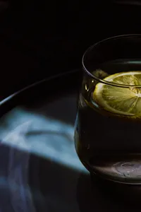close up shot of an alcoholic drink with a lime resting in it, on a dark surface