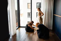 Wedding planners with Weddings & Events by Raina assist bride with her shoes and her dress.