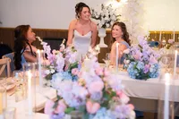 bride and bridesmaids at wedding table with pink and purple floral decor