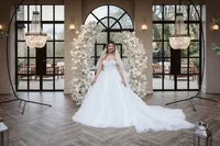 bride in front of white floral arch