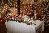 colourful floral wedding table centrepiece and floral wedding arch with fairy light backdrop