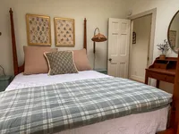 Second-floor bedroom with plaid bedding and floral artwork at Brookside Retreat