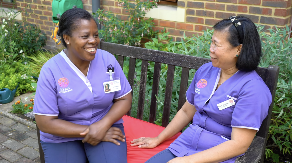 Two carers laughing together in the garden