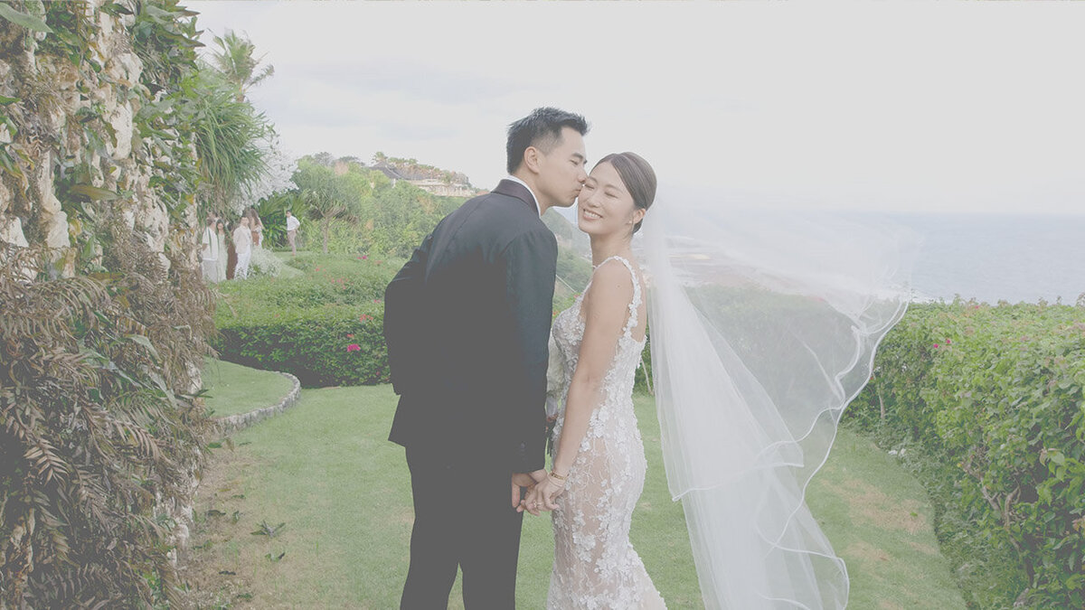 Bride and groom walking across the lawn at their clifftop wedding venue in Bali