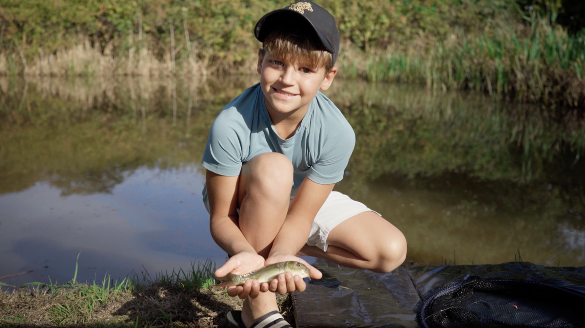 A boy with his catch by the lake