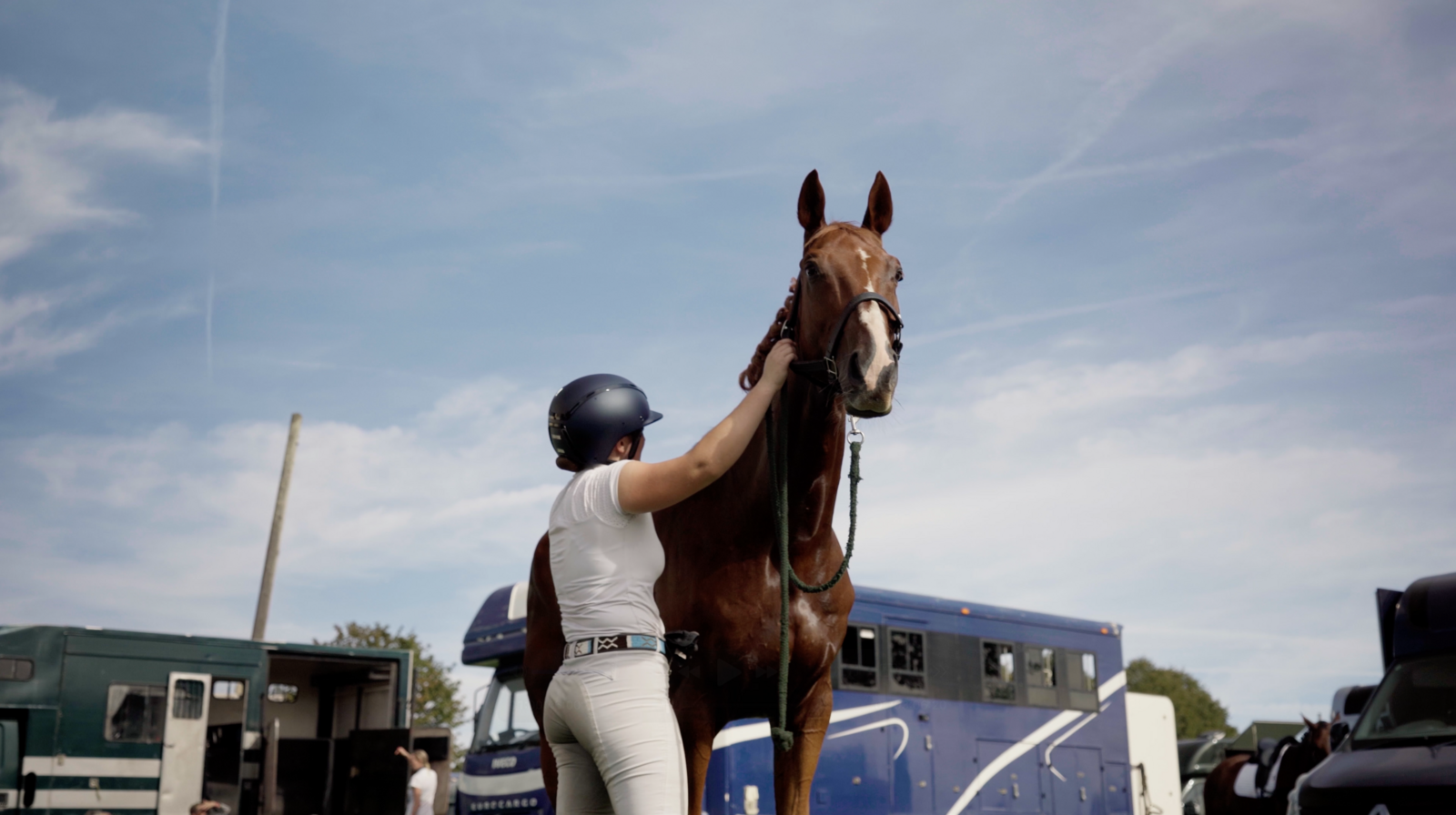 A rider with her horse under a blue sky