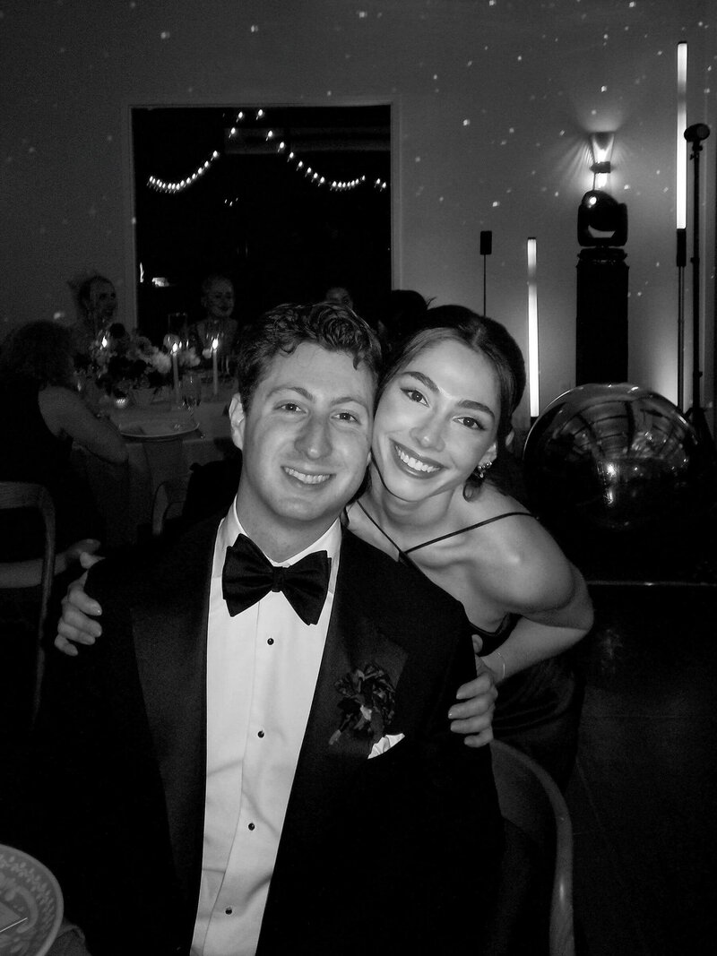 Smiling wedding guests posing together at the reception in black and white