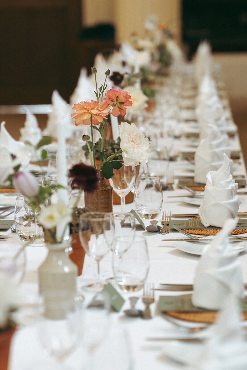 Long wedding breakfast table with flowers, glassware and handwritten place cards