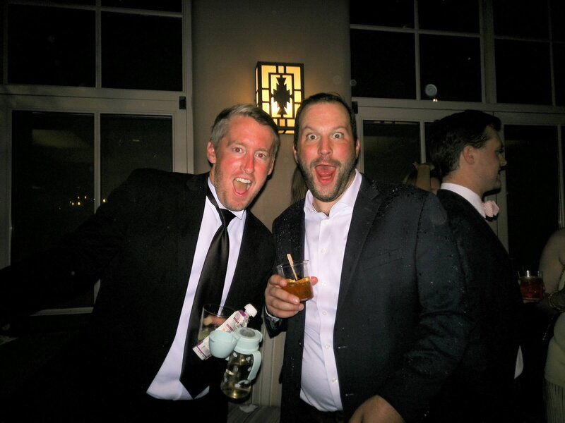 Two wedding guests laughing together at the reception, photographed in color