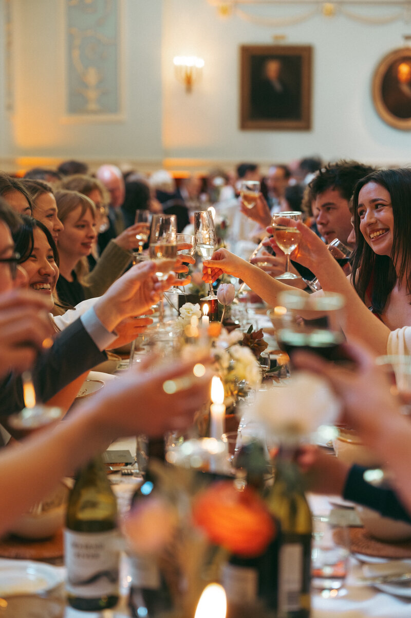 Guests raising their glasses across a candlelit table at the wedding breakfast