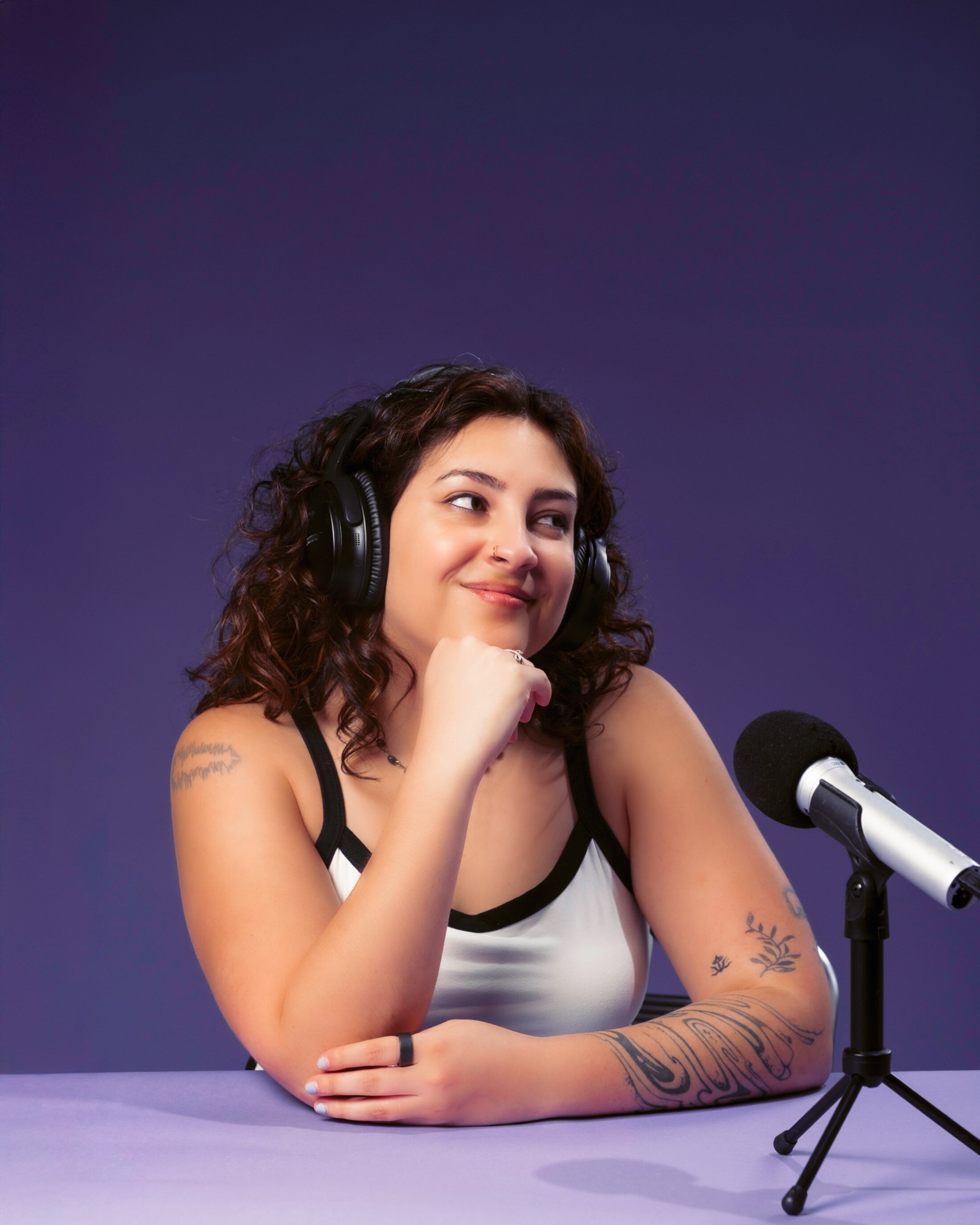 Woman smiles away from the camera next to a podcast microphone.