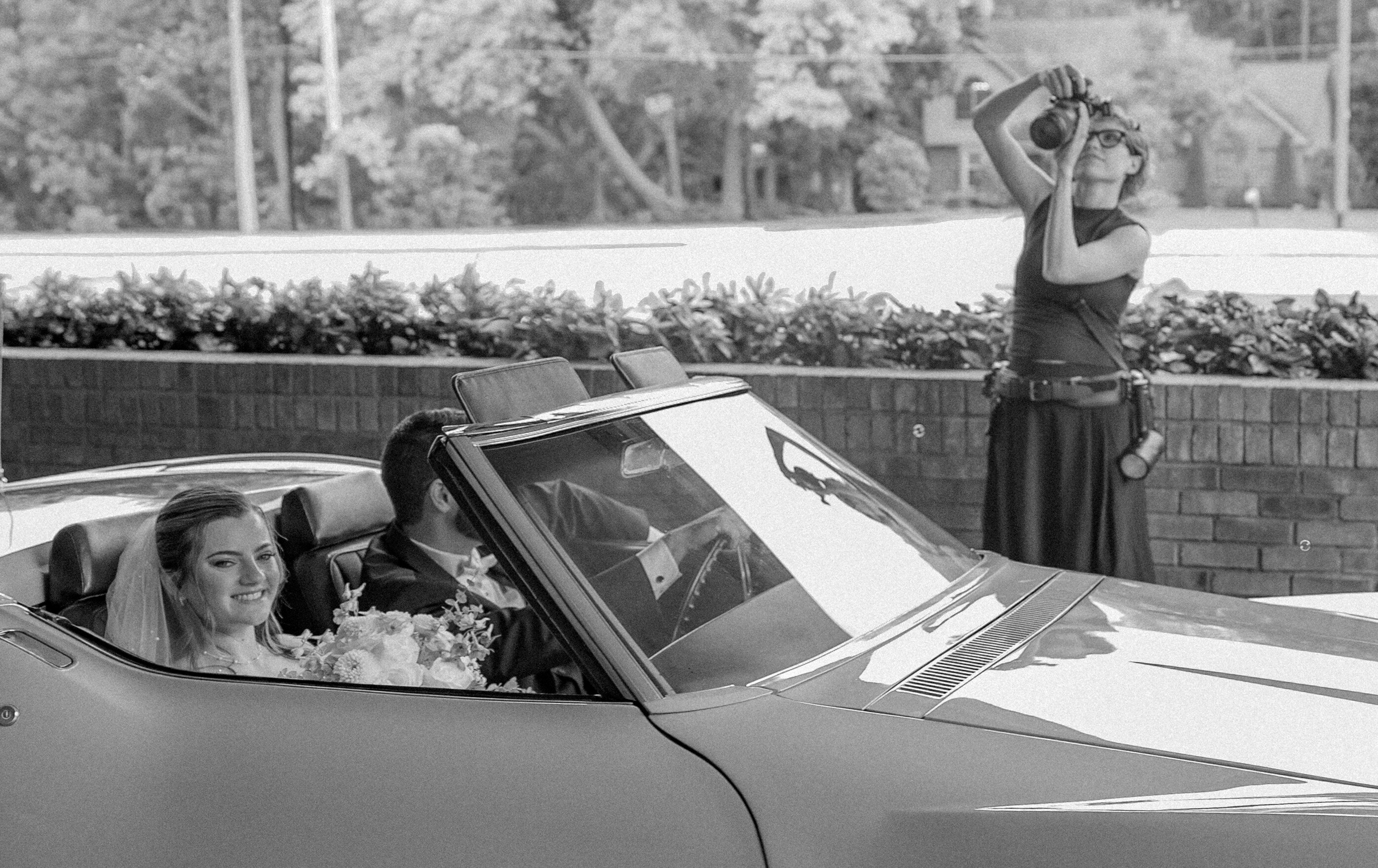 Christy Ditzler of The Wild and Woven Lens photographing a bride and groom driving away after their wedding ceremony in Indianapolis, Indiana